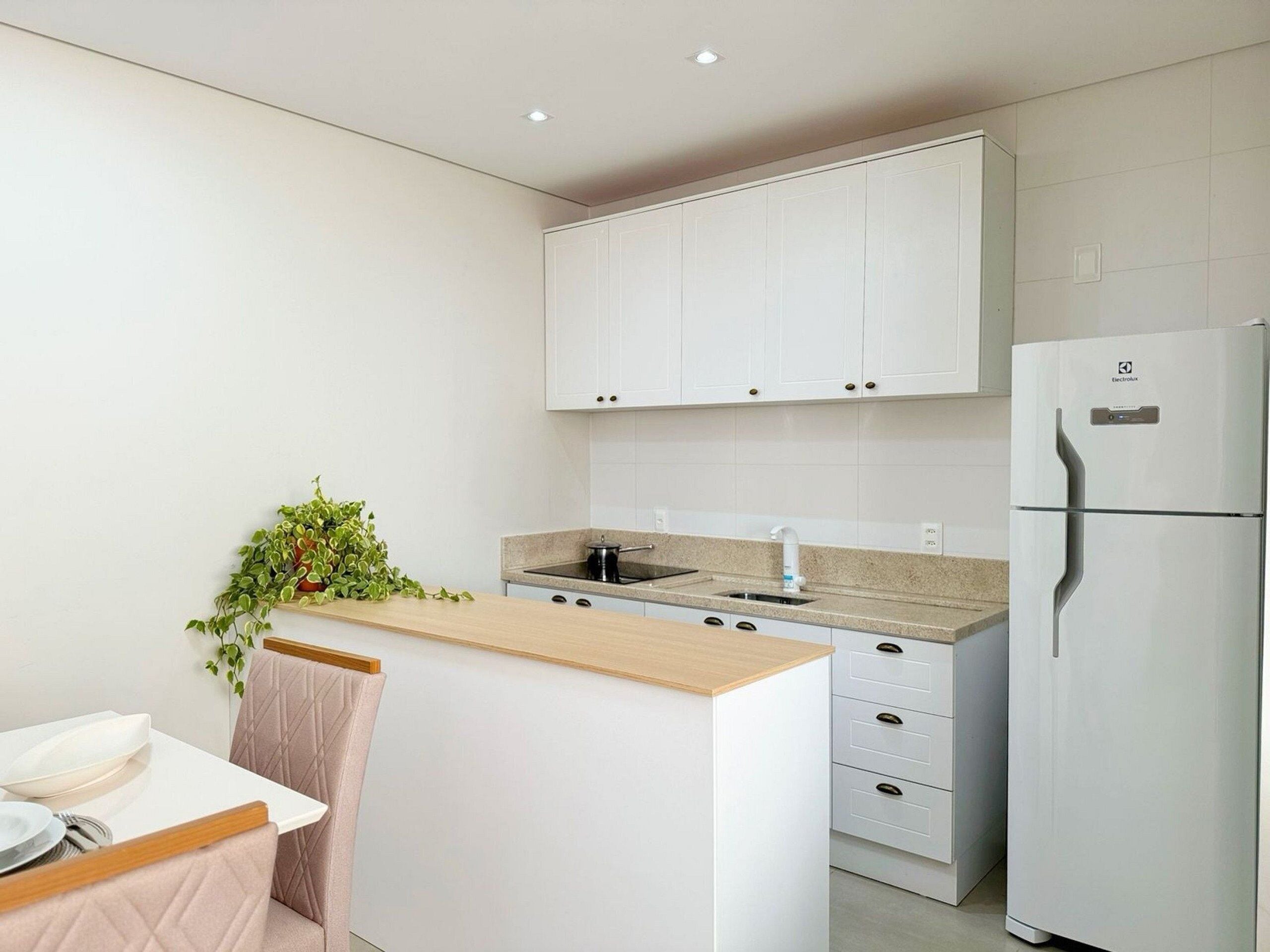 Een moderne keuken met witte kasten, een inbouw eiland, een koelkast en een spoelbak.