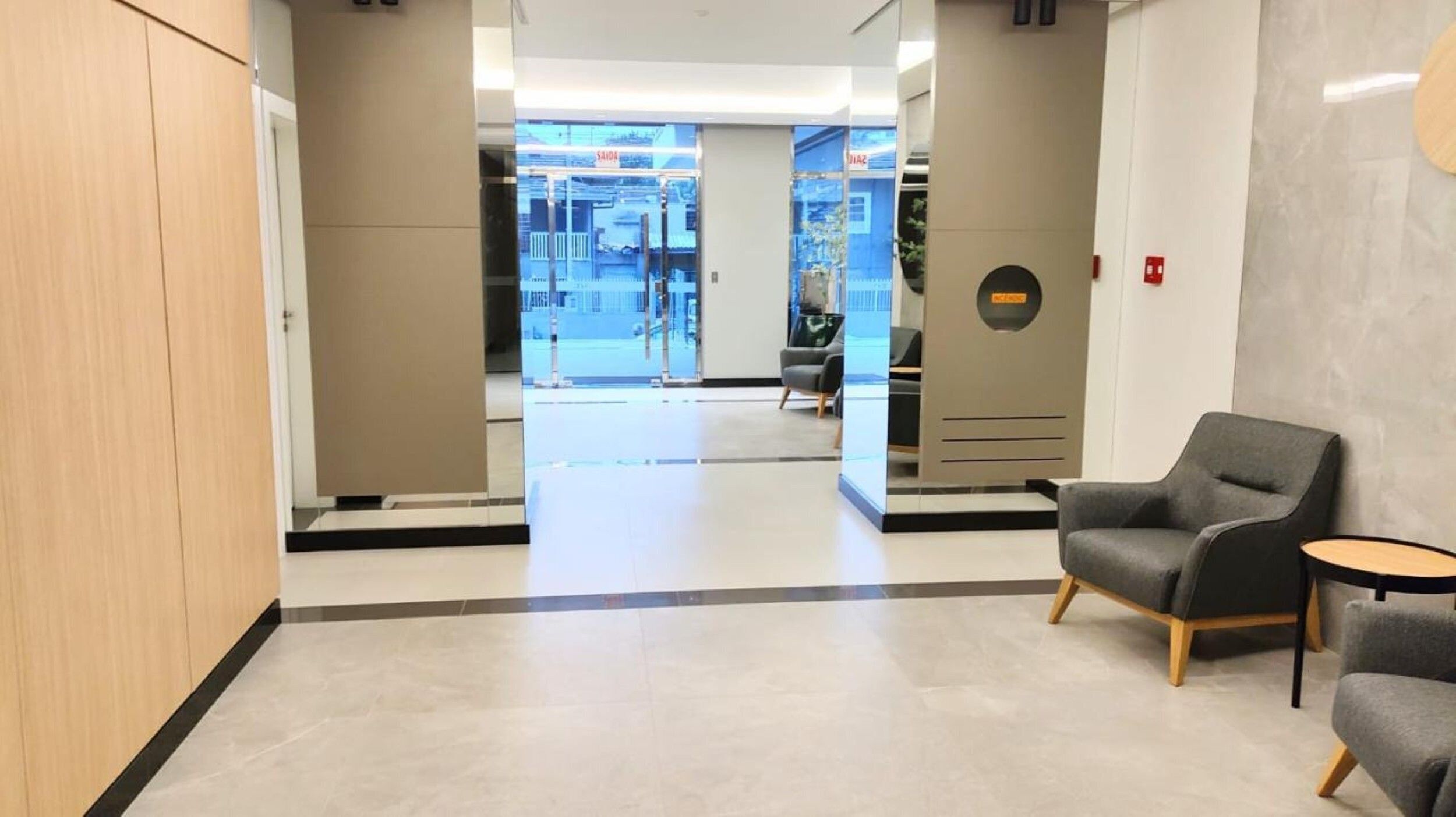 A modern lobby with a reception desk, seating area, and a view of the outside.