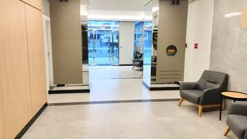 A modern lobby with a reception desk, seating area, and a view of the outside.