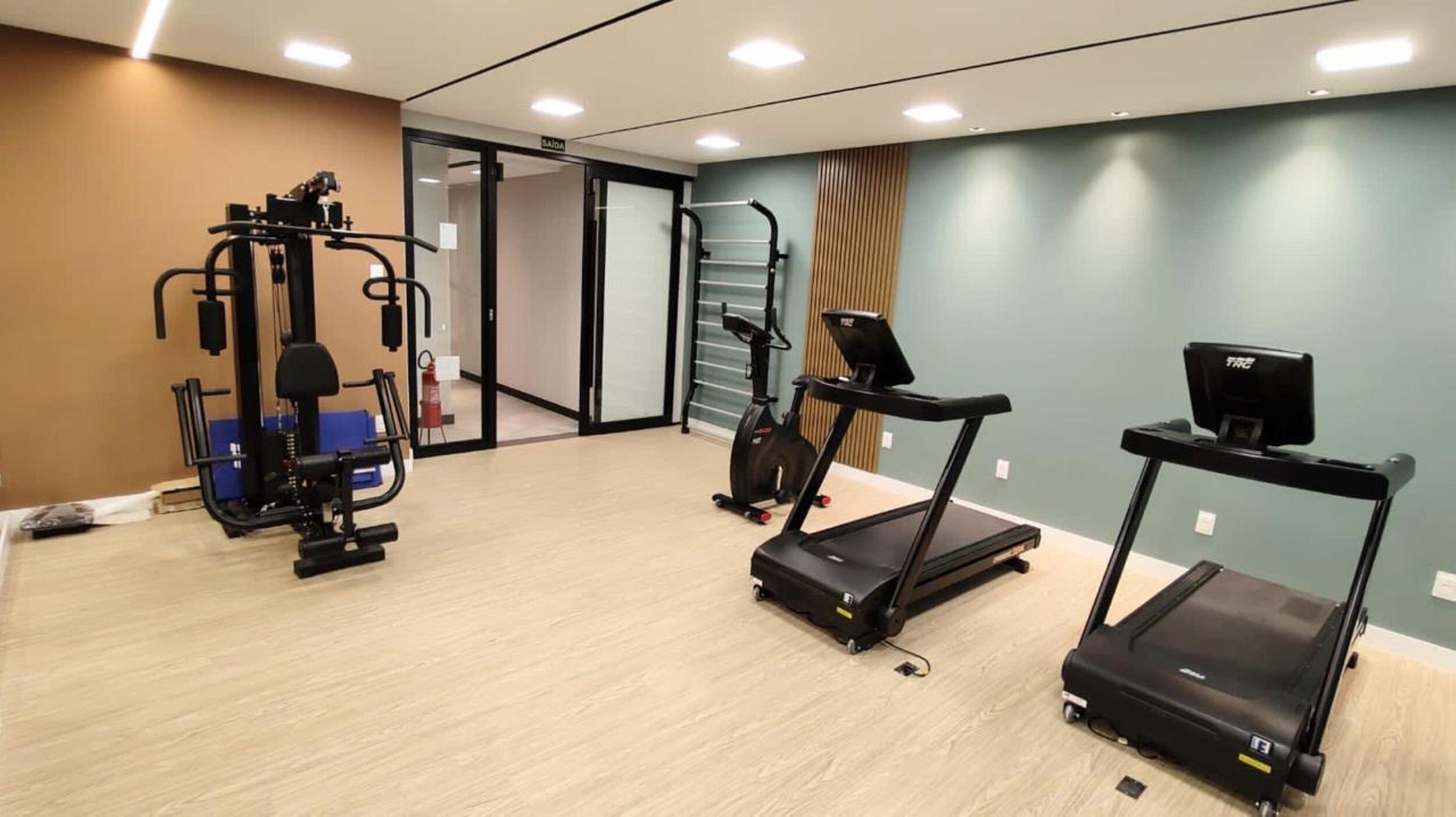 Gimnasio con equipo de ejercicio, incluyendo cinta de correr, elíptica y máquina de pesas.