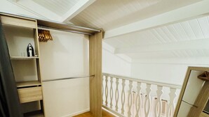 A room with a wooden floor, a white ceiling, and a white railing. There is a wardrobe with a mirror and a shelf with a kettle and cups. - Cosy T2 with mezzanine, swimming pool & beach on foot (Le Gosier)