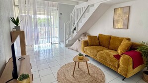 Un salón amplio con sofá, televisión y escalera.