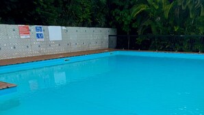 Piscina azul clara con pared de azulejos y borde de madera.