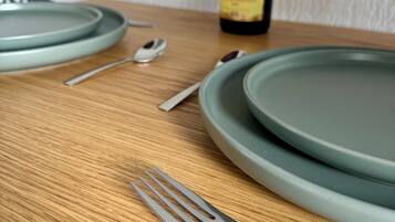 A wooden table with a green plate, a fork, and a bottle of wine in the background.