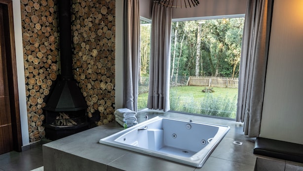 Un baño moderno con una bañera independiente, un estufa de leña y vistas a un patio trasero.