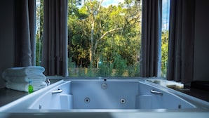 Un baño moderno con una bañera grande, una pila de toallas blancas y una botella de jabón líquido verde.
