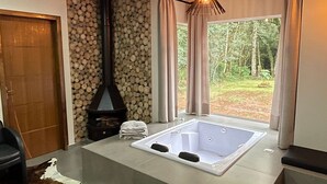 Un baño moderno con una bañera grande, techo de madera y pared de piedra.