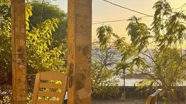 A covered outdoor seating area with two chairs and a tiled floor. - Casa Sunset (El Tránsito)