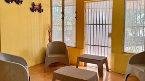 A room with yellow walls, a ceiling fan, two windows with bars, wicker furniture, and an air conditioning unit. - Casa Sunset (El Tránsito)