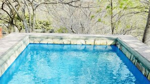 A rectangular swimming pool with clear blue water, surrounded by stone tiles and a stone border. - Casa Sunset (El Tránsito)