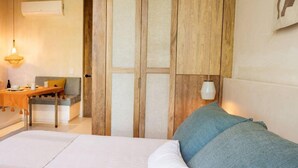 A bedroom with a bed, a wooden wardrobe, a nightstand, a table with a lamp, and a sofa. - Resort-Style Loft in AfloraTulum (Tulum)