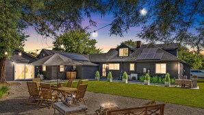 Ein modernes Haus mit einer Terrasse, die einen Esstisch, Stühle und eine Feuerstelle bietet.