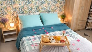 Une chambre à coucher avec un lit, des oreillers, une table de chevet avec une lampe, un plateau contenant des éléments pour le petit-déjeuner et un papier peint à motifs.