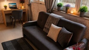 A modern living room with a sofa, a desk with a laptop, and potted plants.