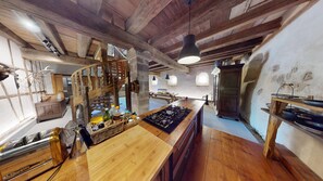 A rustic kitchen with a wooden bar, a gas stove, and a stone wall. - Jardin de l'Abbaye, demeure de charme (Andlau)