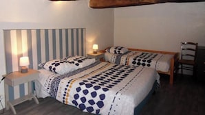 Un dormitorio con dos camas, cabecera a rayas, vigas de madera, lámparas de noche y una silla.