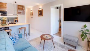 A modern living room with a sofa, a coffee table, and a TV mounted on the wall.