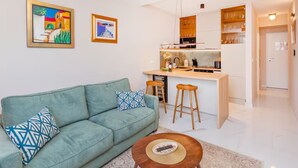 A modern living room with a sofa, a coffee table, and a kitchen area with a bar.