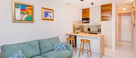 A modern living room with a sofa, a coffee table, and a kitchen area with a bar.