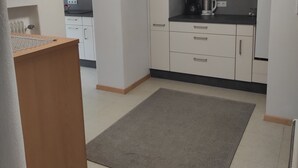Una cocina moderna con armarios blancos, microondas, cafetera y mueble de madera.
