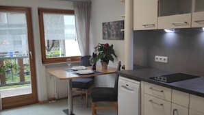 Una cocina moderna con comedor, que incluye un lavavajillas empotrado, armarios y un ventanal con vistas.