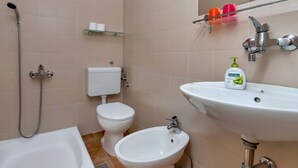 A bathroom with a bathtub, a sink, a bidet, and a toilet. - Villa Paško - Double room with Balcony and Sea View (Podgora)