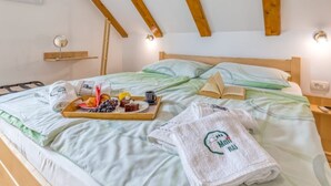 A neatly made bed with a tray of breakfast items, a towel with a logo, and a bedside table with a lamp.