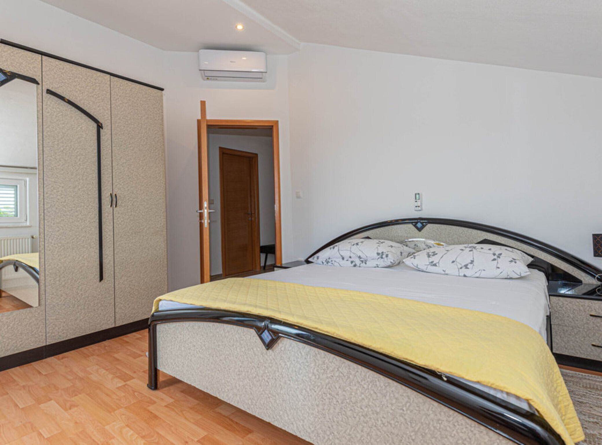 Une chambre à coucher comprenant un lit, une armoire, une porte et un appareil de climatisation.