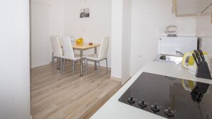 Una cocina moderna con una isla central, armarios blancos y un área de comedor con una mesa y sillas.