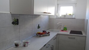 Una pequeña cocina con armarios blancos, una encimera, un fregadero y una ventana sobre él.