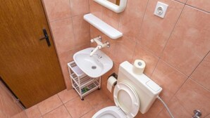 A compact bathroom with a toilet, sink, and shower.