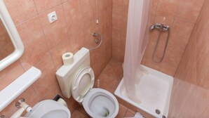 A bathroom with two toilets, a shower, and a sink.
