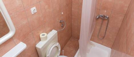 A bathroom with two toilets, a shower, and a sink.