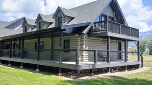 A log cabin with a balcony, a covered porch, and a steeply pitched roof.