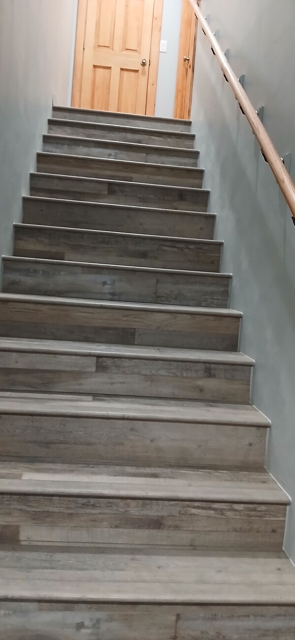 Una escalera de madera con barandilla que conduce a una puerta de madera en la parte superior.