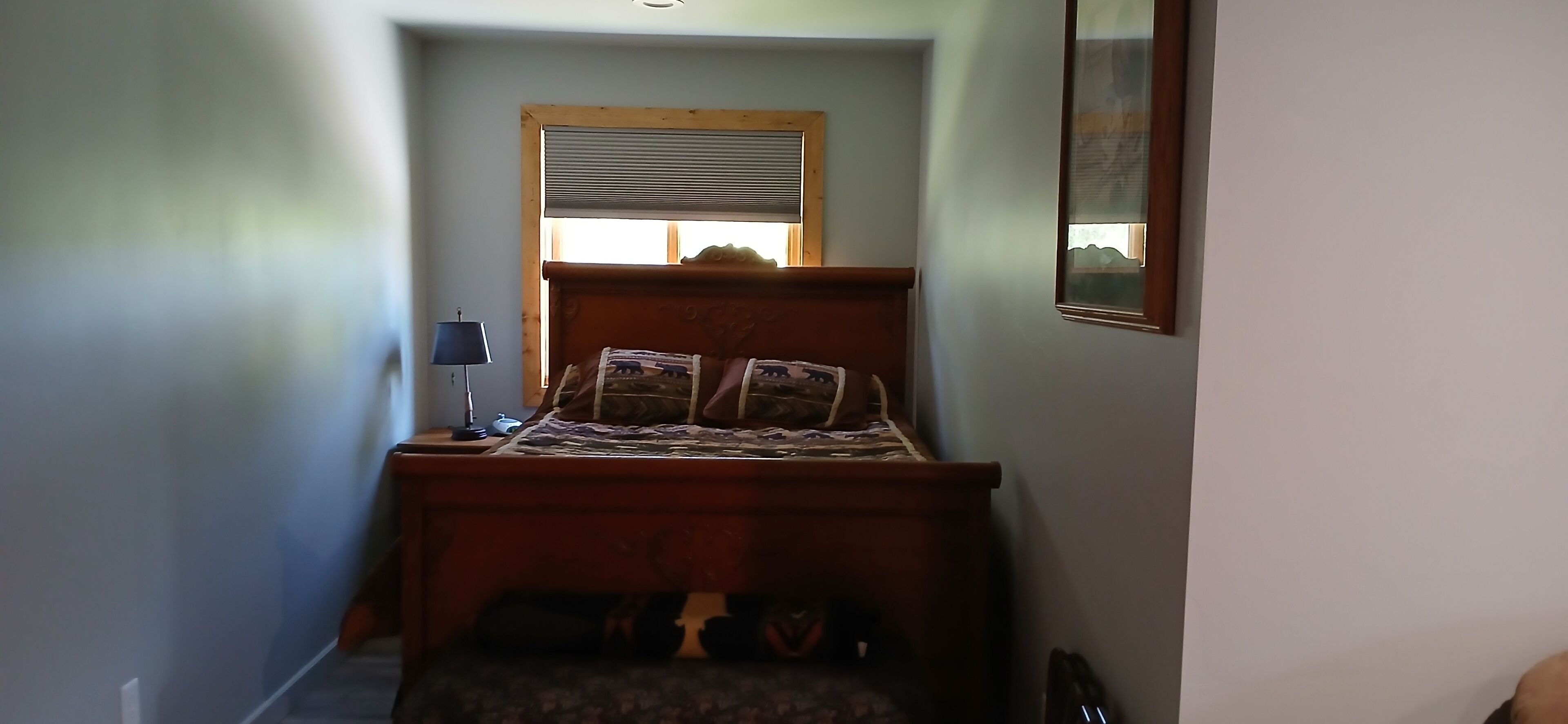 A bedroom with a bed, a nightstand, a lamp, and a window with blinds.