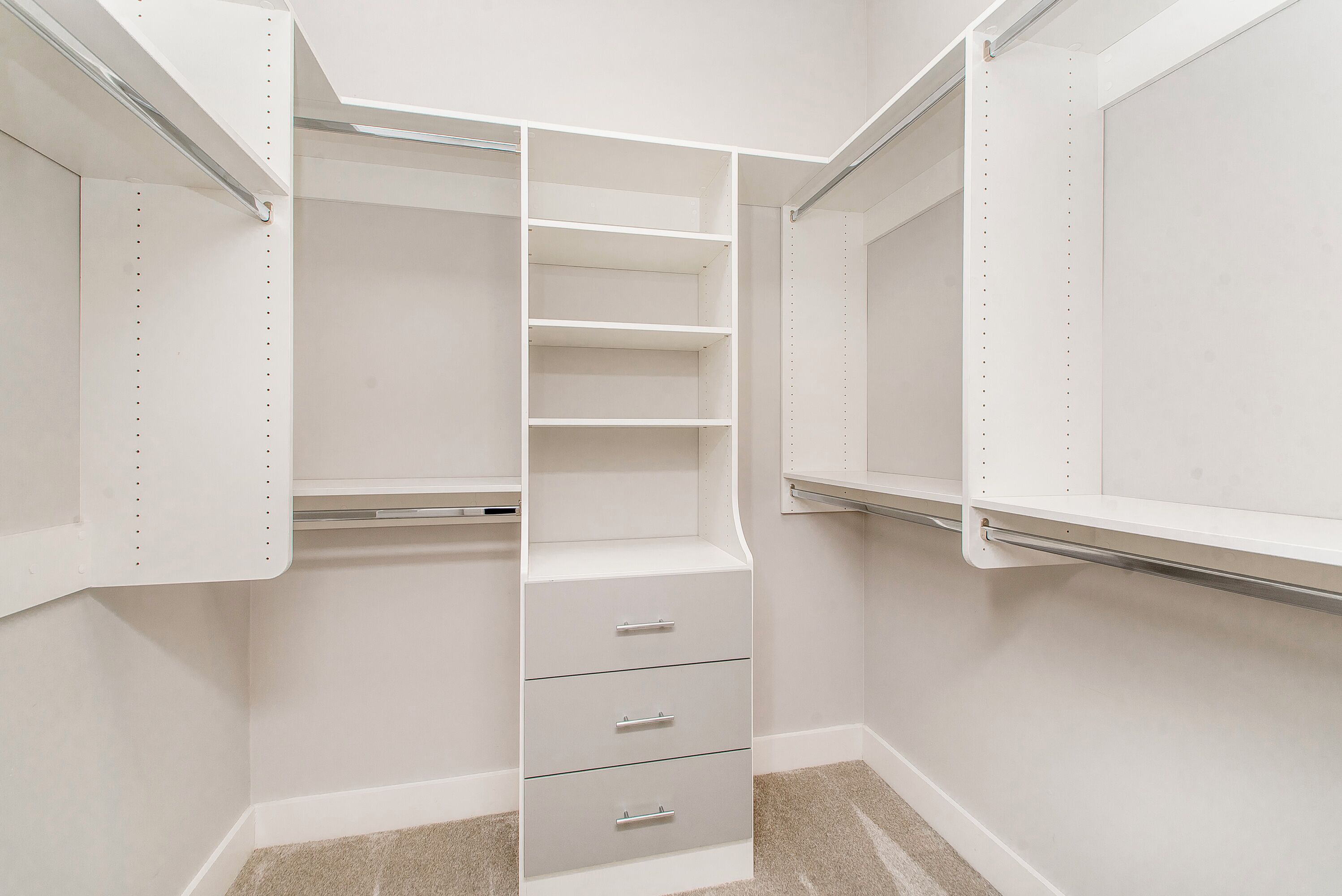 A walk-in closet with open shelves, a hanging rod, and a set of drawers.