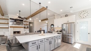 Una cocina moderna con una isla central, electrodomésticos de acero inoxidable e iluminación colgante.
