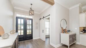 Una habitación amplia con piso de madera, un armario blanco con espejo y una puerta que da a otra habitación.