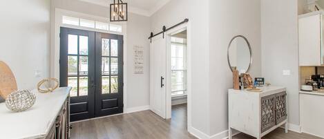A spacious room with a wooden floor, a white cabinet with a mirror, and a door leading to another room.