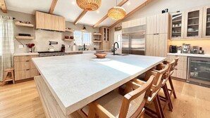 Eine moderne Küche mit einer großen Kochinsel, Holzschränken und einem Edelstahlkühlschrank.