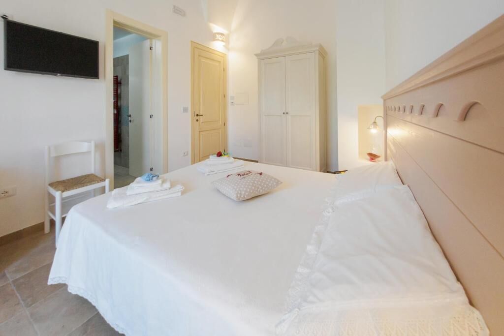 Ein Schlafzimmer mit Bett, einem Sessel, einem Kleiderschrank und einem Fernseher an der Wand.