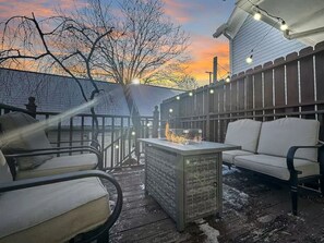 An outdoor seating area with a fire feature, a fence, and a house in the background. - Fun 3 BR Home in Ohio City | Game Room | Sleeps 11 (Cleveland)