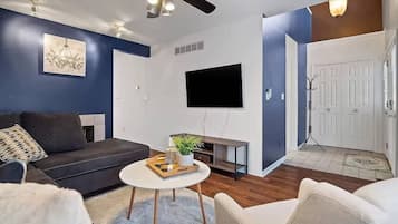 A living room with a sofa, a coffee table, a TV, and a ceiling fan.