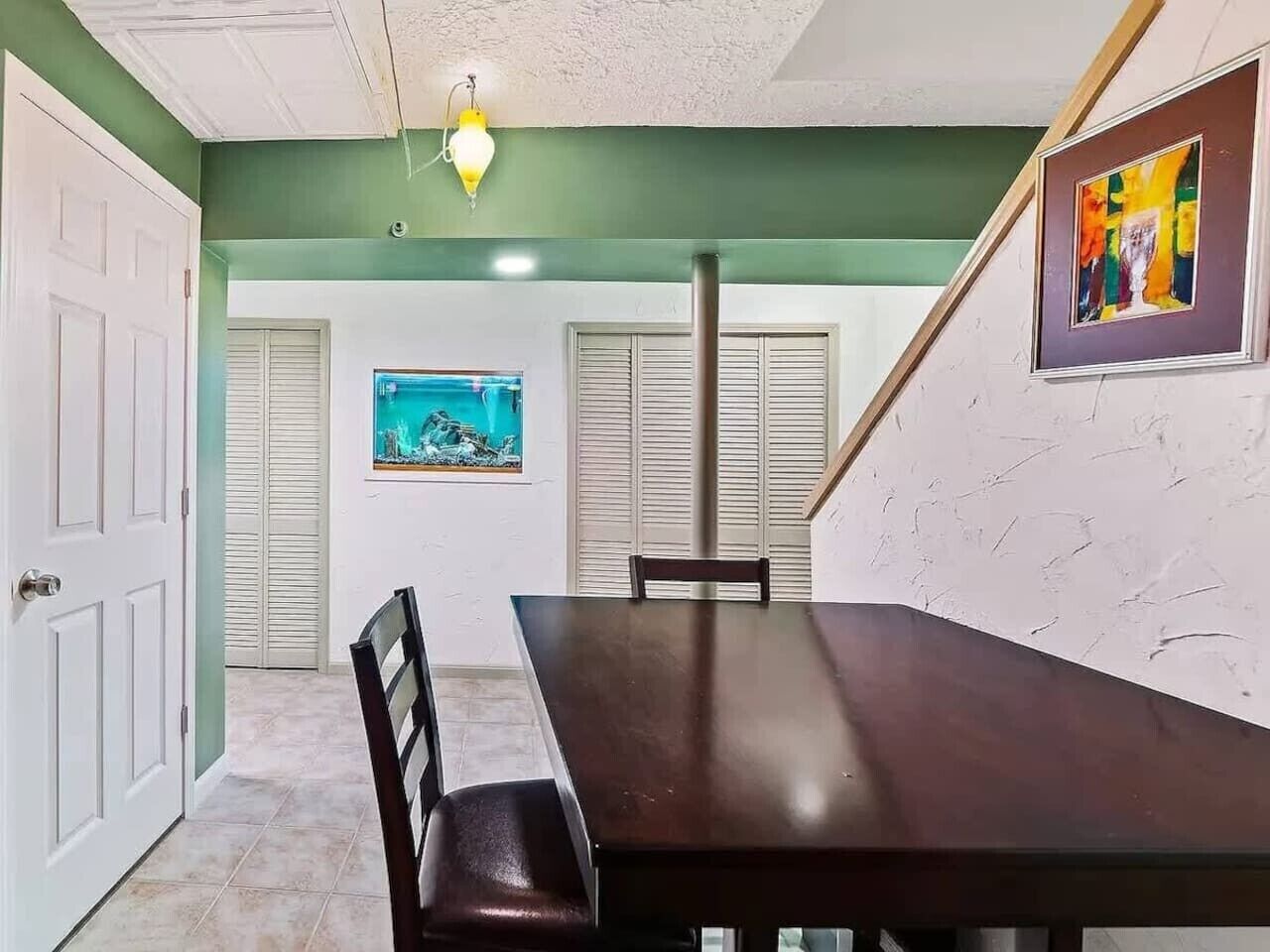 Une salle de conférence avec une longue table et des chaises, un tableau accroché au mur et une porte sur le côté gauche.