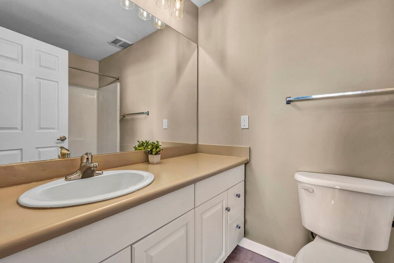 A bathroom with a white sink, a mirror, a toilet, and a towel rack.