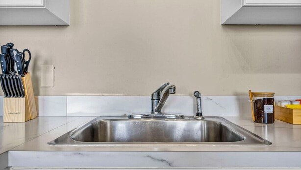 A kitchen with a stainless steel sink, a knife block, and a coffee container. - Colorful 2Bed Apt • Heart of Downtown • Lake Views (Cleveland)