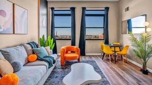 A modern living room with a sofa, armchair, coffee table, and dining area with chairs. - Colorful 2Bed Apt • Heart of Downtown • Lake Views (Cleveland)