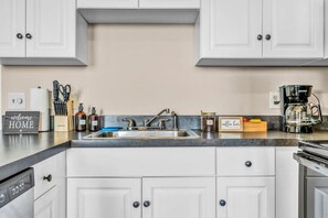 A kitchen with white cabinets, a stainless steel sink, and a coffee maker. - Funky 2B Apt in Downtown Cleveland | FREE Parking (Cleveland)