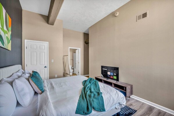 A hotel room with a bed, a television, and a door. - Funky 2B Apt in Downtown Cleveland | FREE Parking (Cleveland)